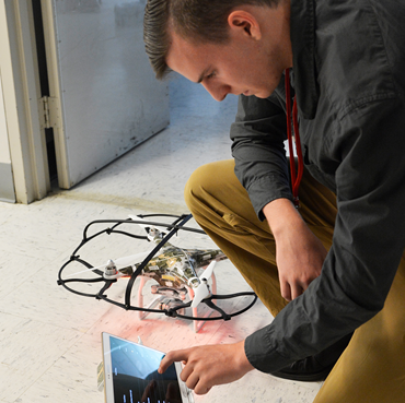 Student working on a tablet and a drone