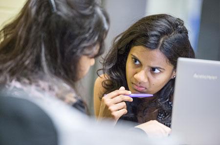 Young woman works with advisor in front of a laptop